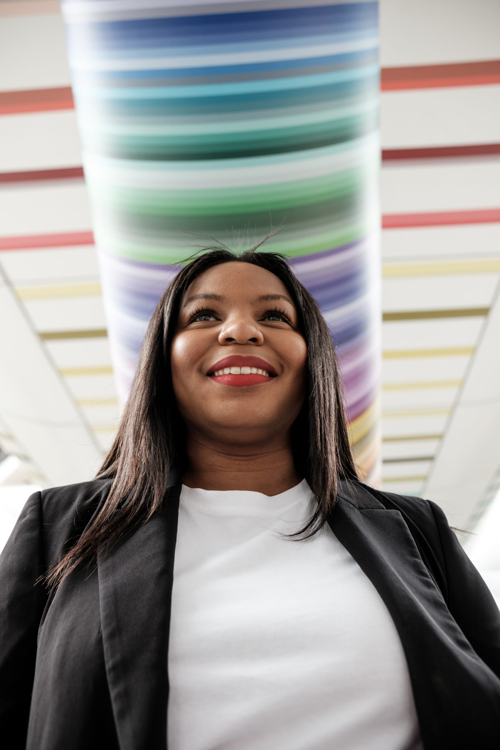 Smiling businesswoman walking in modern building with colorful ceiling