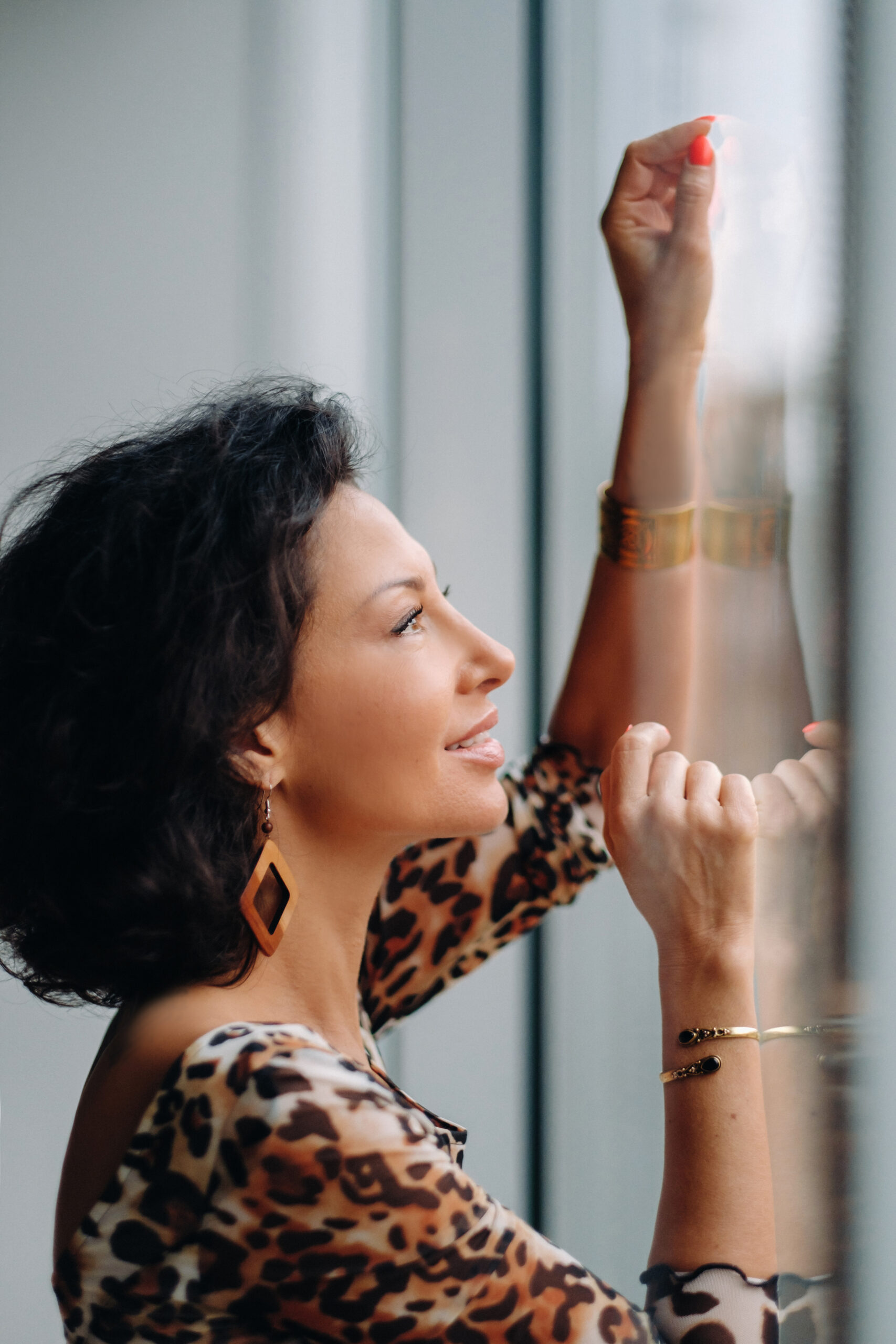 a brunette woman in a tiger dress stands near a large window